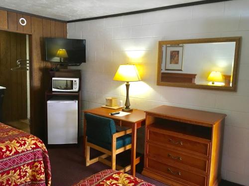 a hotel room with a desk with a bed and a mirror at Granada Inn Motel - Kalkaska in Kalkaska