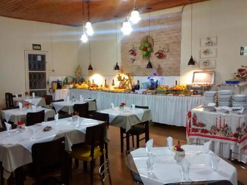 un restaurante con mesas y sillas con manteles blancos en Hotel São Paulo en Poços de Caldas