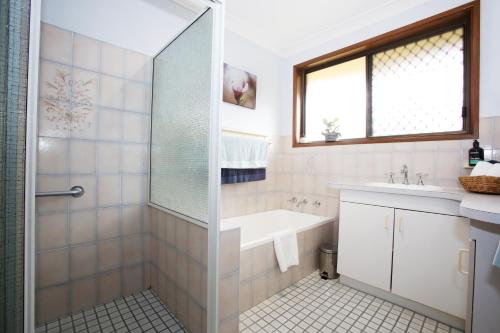 een badkamer met een douche, een wastafel en een bad bij Two 46 Brodie in Coffs Harbour