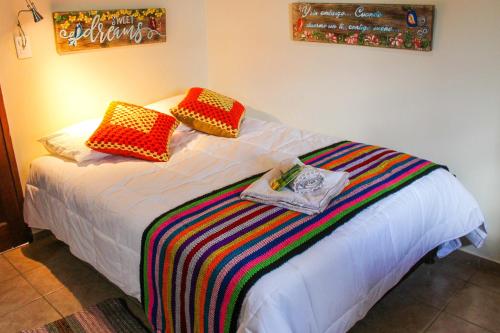 a bed with two colorful pillows on top of it at Cabaña El Mirador Vallegrande in Vallegrande