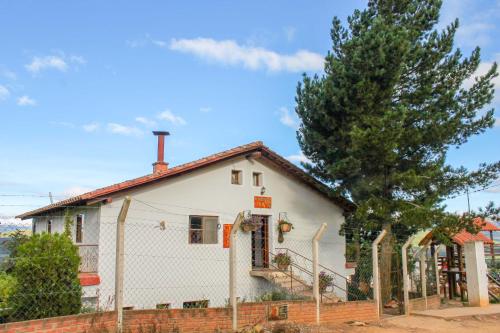 a white house with a fence and a tree at Cabaña El Mirador Vallegrande in Vallegrande