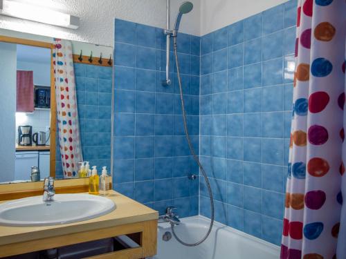 une salle de bain carrelée bleue avec un lavabo et une douche dans l'établissement 26 Praz de l'Ours Vallandry - Paradiski, à Peisey-Nancroix