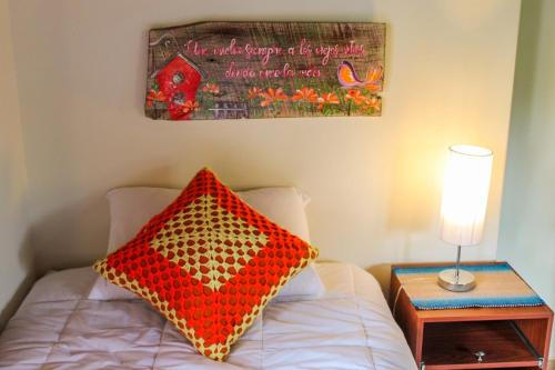 a bedroom with a bed with a red pillow and a table at Cabaña El Mirador Vallegrande in Vallegrande
