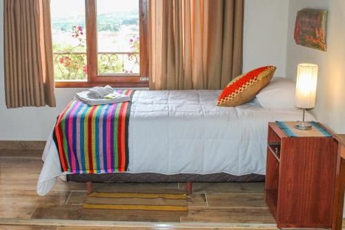 a bedroom with a bed with a lamp and a window at Cabaña El Mirador Vallegrande in Vallegrande
