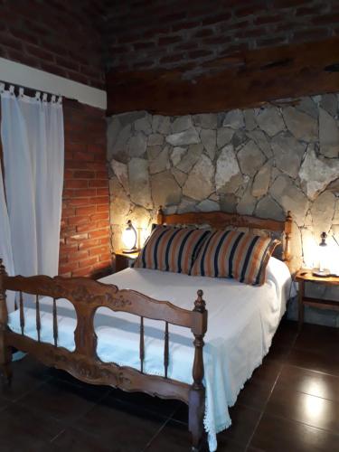 1 dormitorio con cama de madera y pared de piedra en Cabañas Altos del Bosque en Mar del Plata