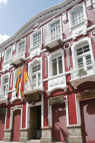 a red and white building with flags in front of it at Hotel Carvallo in Cuenca