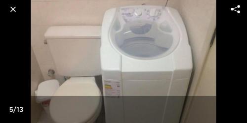 une machine à laver dans une salle de bain à côté des toilettes dans l'établissement Apto em Torres próximo a praia, à Torres