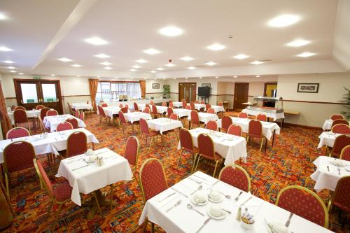 uma sala de jantar com mesas e cadeiras brancas em Ayre Hotel & Ayre Apartments em Kirkwall