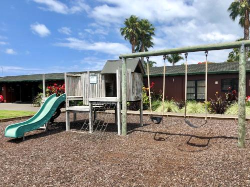 a playground with a slide and a swing at Teal Motor Lodge in Gisborne