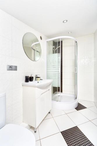 a white bathroom with a shower and a sink at Langery Residence Central Apartments in Odesa