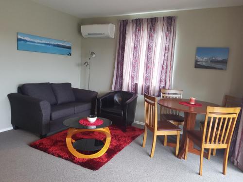 a living room with a couch and a table and chairs at Rosedale Cottages in Twizel