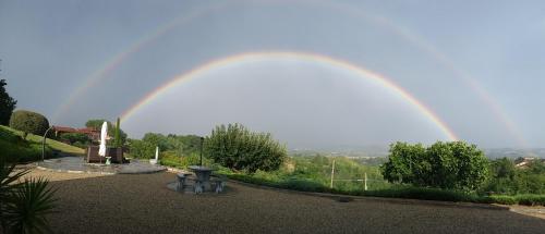 a rainbow in the sky over a garden at B&B Cascina Bellavista in Tigliole