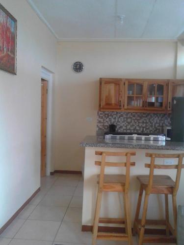 a kitchen with wooden cabinets and a counter with two stools at Sea Shell Palms, Ocho Rios in Ocho Rios