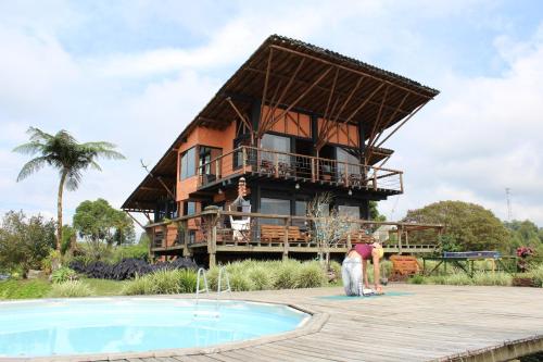 a person standing in front of a house with a pool at Santa Elena de la Colina in Filandia