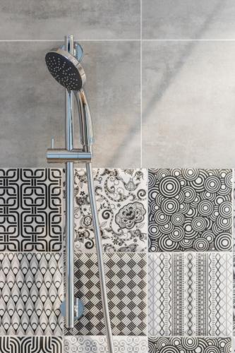 a shower in a bathroom with black and white tiles at Grange Inn in Taitung City