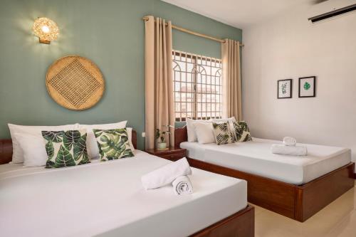 2 camas en una habitación con ventana en Babel Siem Reap Guesthouse en Siem Riep