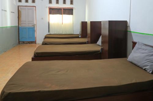 a group of three beds in a room at Guest House Rumah Lombok Syariah in Mataram