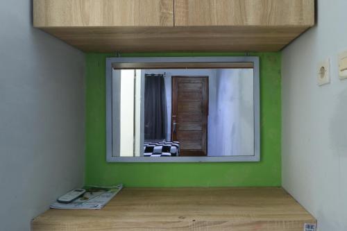a mirror on a green wall in a room at Guest House Rumah Lombok Syariah in Mataram