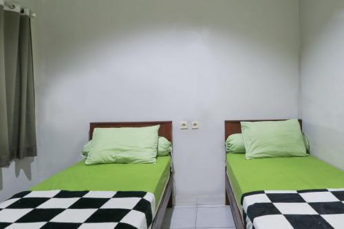 two beds in a room with green and white sheets at Guest House Rumah Lombok Syariah in Mataram