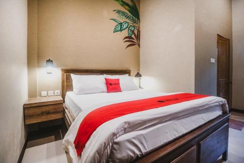 a bedroom with a large bed with a red blanket at RedDoorz Plus near Mall Slipi Jaya in Jakarta