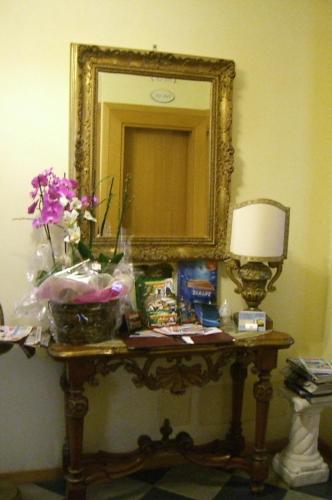 a table with a mirror and flowers on it at Hotel Lido in Lido di Jesolo