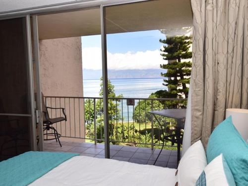 Deluxe Oceanview Maui Studio..New & Updated في Kahana: غرفة نوم بسرير وشرفة مطلة