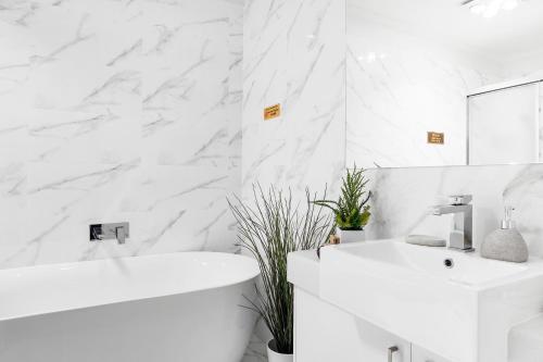 La salle de bains blanche est pourvue d'une baignoire blanche et d'un lavabo. dans l'établissement Olinda Village Apartment - A2, à Olinda