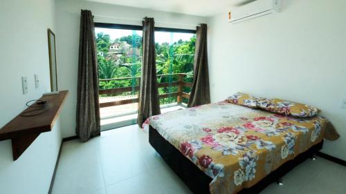 a bedroom with a bed and a window with a balcony at Casa Marilù in Morro de São Paulo