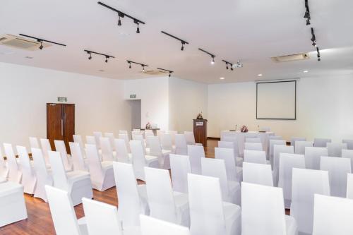 an empty room with white chairs and a projection screen at Jetwing Sea in Negombo