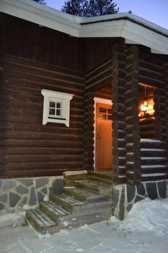 a front door of a log house with a snow covered porch at Chalet Suomukka in Suomutunturi