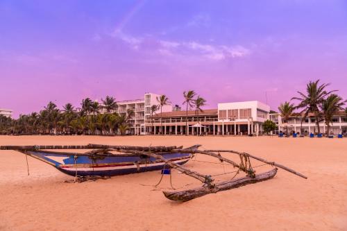 a boat sitting on the beach in front of a resort at Jetwing Sea in Negombo