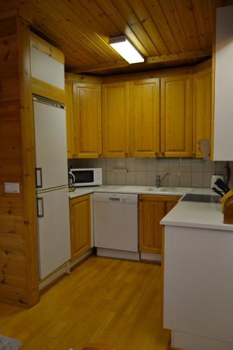 a kitchen with a white refrigerator and wooden cabinets at Chalet Suomukka in Suomutunturi