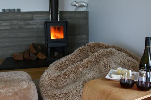 a living room with a fireplace and a table with a blanket at The Cube in Kakanui