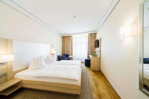 a hotel room with a bed with white sheets at Flair Hotel zum Schiff in Meersburg