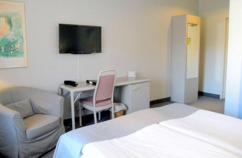 a hotel room with a bed and a desk and a tv at Hotell Erikslund in Ängelholm