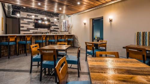 a restaurant with wooden tables and chairs and a bar at Best Western Premier Ankeny Hotel in Ankeny