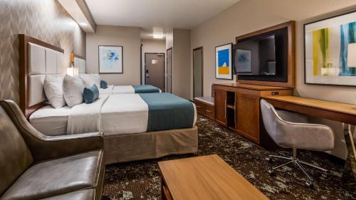 a hotel room with a bed and a desk and a tv at Best Western Premier Ankeny Hotel in Ankeny