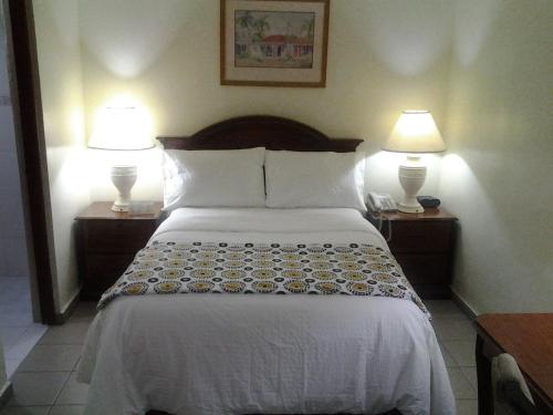 1 cama en una habitación de hotel con 2 lámparas en Micro Hotel Condo Suites, en Santo Domingo