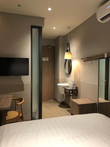 a bedroom with a bed and a bathroom with a sink at Citrip Hotel Simpang Lima in Semarang