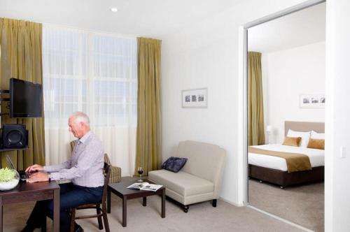 an older man sitting at a desk in a hotel room at Quest on London in Hamilton
