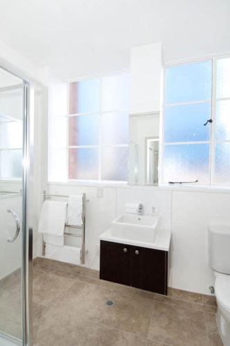 a bathroom with a sink and a toilet and a mirror at Quest on London in Hamilton