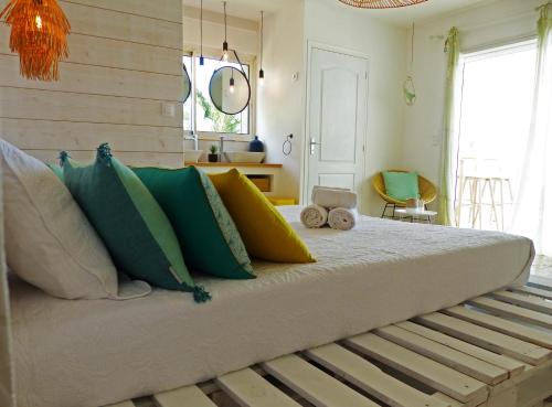a large bed with colorful pillows in a room at LA BOHEME, résidence de 5 appartements avec piscine, vue océan, Petite Ile in Petite Île