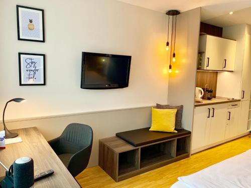 a room with a table and a tv on the wall at zeitwohnhaus SUITE-HOTEL & SERVICED APARTMENTS in Erlangen