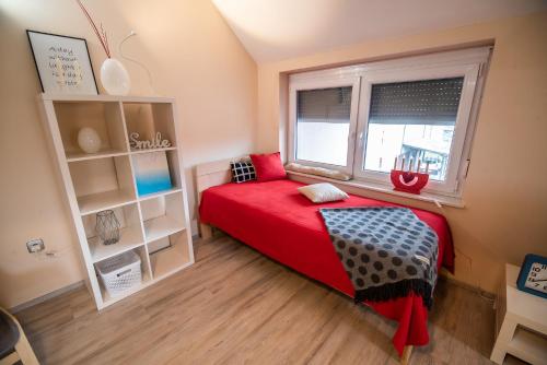 a small bedroom with a red bed and a window at Apartment Stil near Terme Paradiso in Dobova