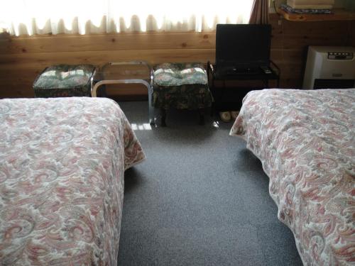 a room with two beds and a desk and a laptop at Turtle Inn Nikko in Nikko