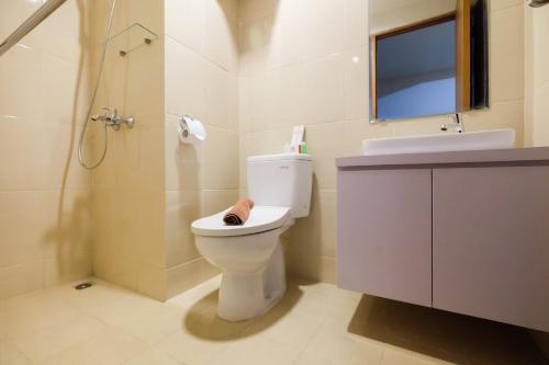 une salle de bain avec toilettes, lavabo et douche dans l'établissement Bright and Stylish 1BR The Oasis Apartment Cikarang By Travelio, à Cikarang
