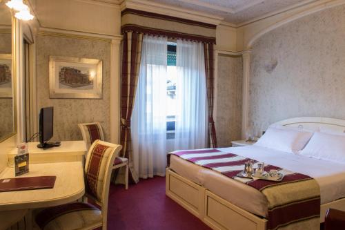 a hotel room with a bed and a desk and a window at Hotel Colomba d'Oro in Verona