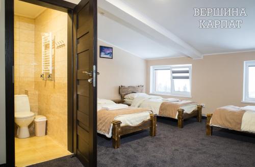 a room with three beds and a toilet and a bathroom at Vershyna in Dragobrat