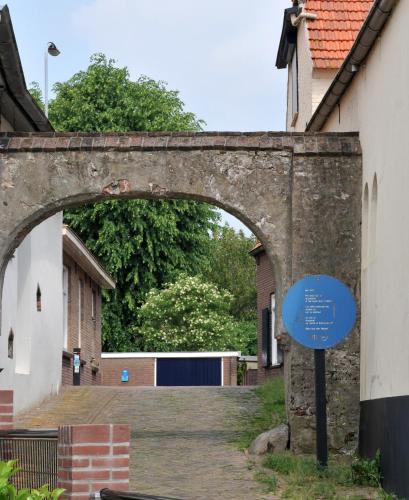 an archway over a street with a blue sign at De Smidse in Lobith