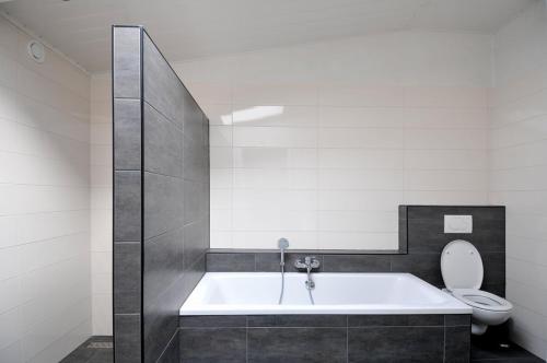 a bathroom with a bath tub and a toilet at De Smidse in Lobith